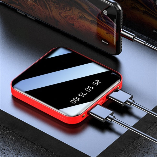 Square, red-cased portable power bank with a reflective black digital display, simultaneously charging two devices via.