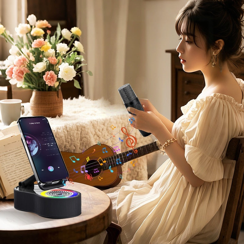 Black phone stand and Bluetooth speaker with RGB lights holds a smartphone, used by a woman holding a handheld microphone.
